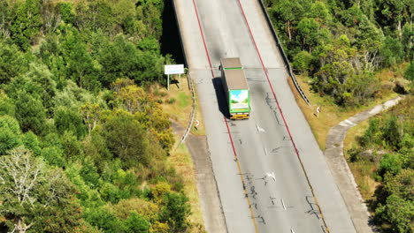 Forwards-tracking-of-truck-with-trailer-zigzagging-on-road-and-passing-around-other-vehicles.-High-angle-view.-South-Africa