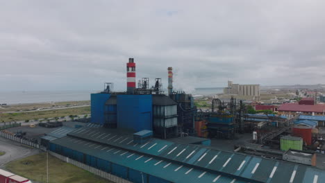 Industrial-plant-on-seaside.-Slide-and-pan-aerial-footage-of-factory-with-chimneys.-Port-Elisabeth,-South-Africa