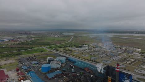 Aerial-panoramic-view-of-industrial-sites-in-flat-landscape.-Traffic-on-roads.-Tilt-down-on-chemical-factory.-Port-Elisabeth,-South-Africa