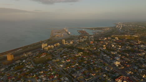 Slide-and-pan-shot-of-industrial-and-logistic-site-at-sea-coast.-Evening-aerial-footage-of-port-and-surrounding-borough.-Port-Elisabeth,-South-Africa