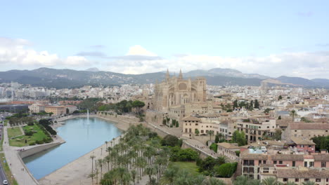 AERIAL:-Palma-Cathedral-Wide-shot-in-Daylight,-Blue-Sky-with-Traffic-and-Tourists-on-Tropical-Island-Mallorca,-Spain-on-Sunny-Day-Vacation,-Travel,-Sunny