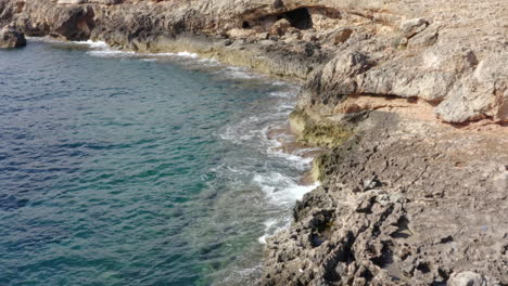 Antenne:-Wunderschönes-Ozeanblaues-Wasser-An-Der-Felsenküste-Auf-Der-Tropischen-Insel-Mallorca,-Spanien-Urlaub,-Reise,-Sonnig,-Wellen