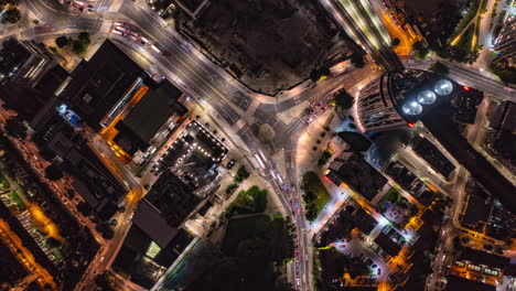 Aerial-birds-eye-overhead-top-down-rising-hyperlapse-footage-of-traffic-in-streets-Elephant-and-Castle-district.-Busy-road-intersection-at-night,-long-exposure-time-blurring-motion.-London,-UK