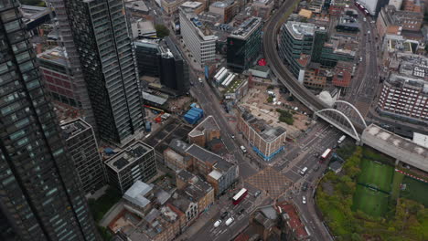 Aerial-footage-of-traffic-on-road-intersection-in-city.-Fly-along-tall-office-buildings-an-view-at-urban-neighbourhood.-London,-UK