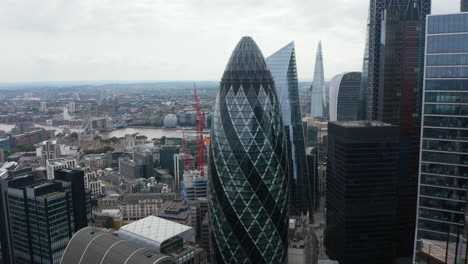 Elevated-view-of-Gherkin-skyscraper.-Backwards-reveal-of-group-of-modern-tall-office-buildings-in-City-financial-hub.-London,-UK