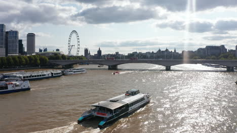 Vorwärtsverfolgung-Des-Schiffes,-Das-Auf-Der-Glitzernden-Wasseroberfläche-Der-Themse-Schwimmt.-Blick-Gegen-Sonnenschein.-Silhouette-Von-London-Eye-Und-Houses-Of-Parliament-über-Hellen-Wolken-Im-Himmel.-London,-Vereinigtes-Königreich