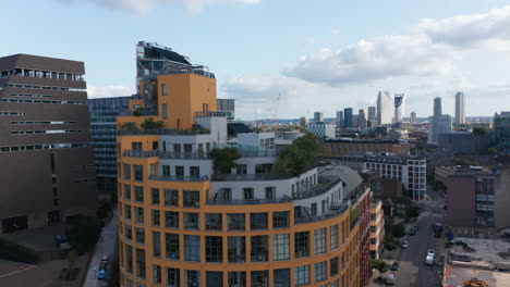 Crane-up-footage-of-Bankside-Lofts-apartment-building.-Rounded-building-with-colourful-facade.-Group-of-skyscrapers-in-background.-London,-UK