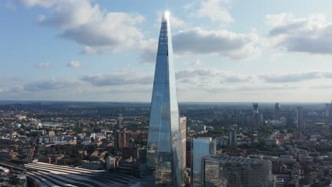 Elevated-footage-of-The-Shard-building.-Tall-modern-glossy-glass-covered-skyscraper-at-London-Bridge-train-station.-Panoramic-aerial-view-of-city.-London,-UK