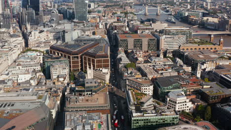 Aerial-panoramic-view-of-building-in-The-City-f-London-district.-High-angle-view-of-traffic-in-streets.-Towe-Bridge-and-skyscrapers-in-background.-London,-UK