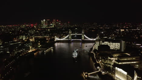 Luftaufnahme-Der-Tower-Bridge-über-Die-Themse-Bei-Nacht.-Berühmtes-Wahrzeichen,-Das-Von-Hellem-Licht-Beleuchtet-Wird.-London,-Vereinigtes-Königreich