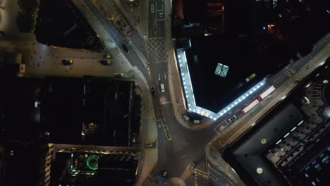 Aerial-birds-eye-overhead-top-down-panning-view-of-low-traffic-in-streets-at-night.-Cars-driving-through-crossroad-in-star-shape.-London,-UK