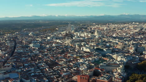 Aerial-panoramic-descending-footage-of-cityscape.-Various-buildings-in-midtown.-Mountain-range-in-distance.