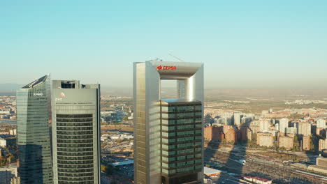 Slide-and-pan-shot-of-modern-high-rise-office-buildings-towering-above-other-town-development.-Cuatro-Torres-Business-area-on-sunny-day.