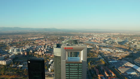 Aerial-shot-of-top-of-modern-skyscrapers-in-Cuatro-Torres-Business-Area.-Town-development-with-housing-estates,-industrial-and-logistic-site-lit-by-afternoon-sun-in-background.