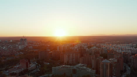 Backwards-fly-above-large-city.-Aerial-view-of-multistorey-apartment-houses-in-housing-estate-against-setting-sun.