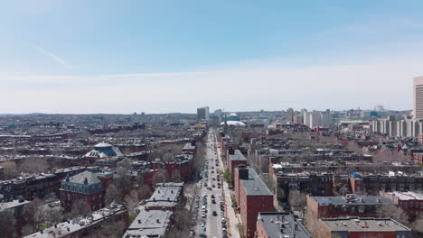 Aerial-ascending-footage-of-buildings-in-urban-neighbourhood.-Long-straight-street-leading-along-red-brick-apartment-houses.-Boston,-USA