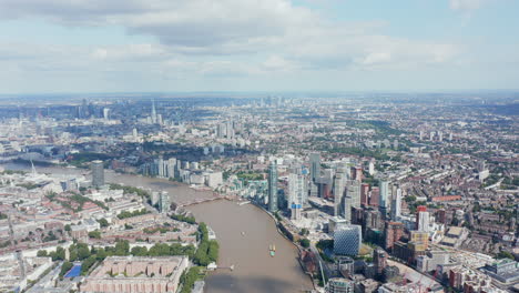 Aerial-view-of-variety-of-buildings-along-Thames-river.-Tall-modern-office-buildings-on-one-bank-and-lower-apartment-buildings-in-housing-estate-on-the-other.-London,-UK