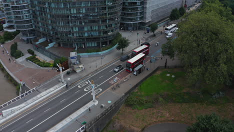 Descending-footage-of-traffic-on-street.-Typical-red-double-deckers-providing-public-transportation.-Modern-apartment-buildings-along-street.-London,-UK