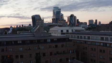Rising-footage-of-city-landmarks.-Revealing-famous-Tower-Bridge-and-skyscrapers-in-City-against-sunset-sky.-London,-UK