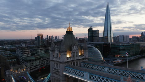 Fly-around-top-walkway-and-roof-of-Tower-Bridge.-Evening-panoramic-view-of-skyscrapers-on-River-Thames-banks.-London,-UK