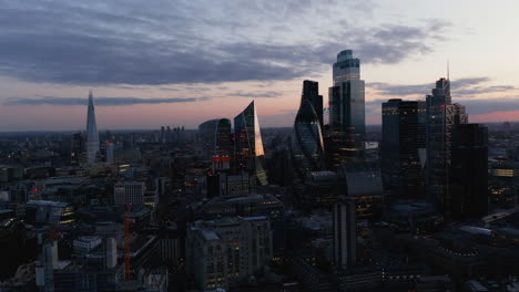 Slide-and-pan-shot-of-group-of-skyscrapers-in-City-business-district.-Tall-futuristic-buildings-against-twilight-sky.-London,-UK