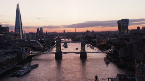 Ascending-footage-of-bridges-across-Thames-river-against-twilight-sky.-Illuminated-famous-Tower-Bridge-in-foreground.-London,-UK