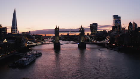 Crane-up-footage-of-famous-Tower-Bridge-over-River-Thames.-Illuminated-historic-landmark-against-twilight-sky.-London,-UK