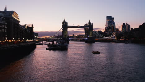 Slide-and-pan-footage-of-Tower-bridge-in-evening.-Low-flight-above-water-of-River-Thames-at-Butlers-Wharf-Pier.-London,-UK