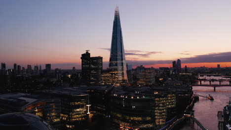 Forwards-fly-above-evening-city.-Heading-towards-Shard-skyscraper.-Modern-tall-office-building-against-colourful-twilight-sky.-London,-UK