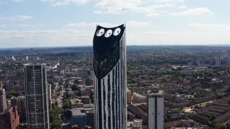 Fly-around-tall-building-with-wind-turbines-on-top-as-source-of-sustainable-energy.-Strata-skyscraper-towering-above-city.-London,-UK