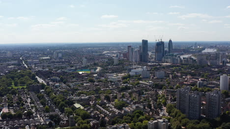 Ascending-panoramic-footage-of-large-city.-Housing-district-and-tall-office-buildings-in-distance.-London,-UK