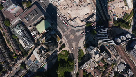 Aerial-birds-eye-overhead-top-down-descending-view-of-vehicles-standing-in-front-of-road-intersection-next-to-Strata-skyscraper.-London,-UK