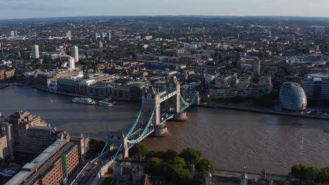 Aerial-panoramic-view-of-famous-historic-landmark,-Tower-Bridge-across-Thames-river.-Buildings-in-large-city-in-evening-golden-hour.-London,-UK
