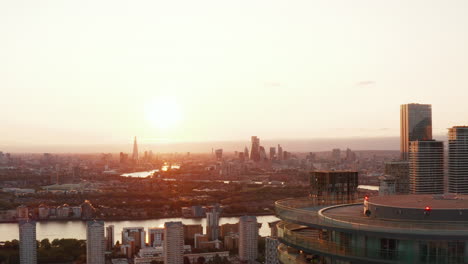 Backwards-reveal-of-top-of-Arena-Tower-building.-Panoramic-view-of-city-with-skyline-against-sunset-sky.-London,-UK