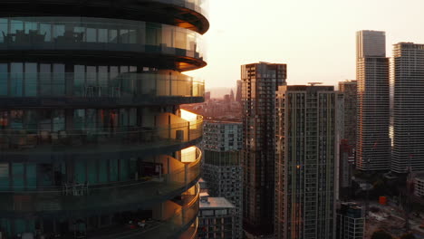 Tall-modern-building-with-glass-walls.-Revealing-skyscrapers-in-business-hub-against-sunset.-London,-UK