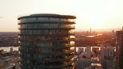 Ziehen-Sie-Aufnahmen-Des-Futuristischen-Zylindrischen-Mehrfamilienhaus-Arena-Turms-Und-Der-Skyline-Vor-Dem-Sonnenuntergangshimmel-Im-Hintergrund-Zurück.-London,-Vereinigtes-Königreich