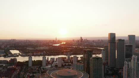 Aerial-panoramic-footage-of-city-in-sunset-time.-Backwards-reveal-of-skyscrapers-in-Canary-Wharf-financial-hub.-London,-UK