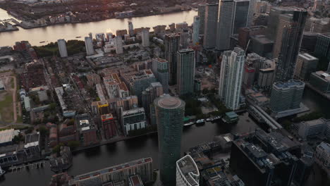 Vista-De-ángulo-Alto-Del-Canal-De-Agua-Entre-Edificios-En-El-Distrito-Comercial-De-Canary-Wharf.-Vista-Aérea-En-El-Atardecer.-Londres,-Reino-Unido