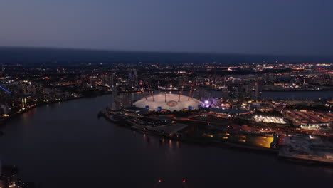 Evening-aerial-view-of-Millennium-Dome.-O2-arena-at-night.-Illuminated-city-streets-and-buildings.-London,-UK