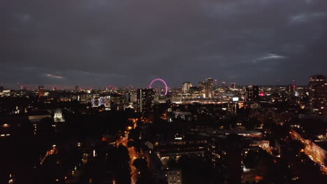 Toma-Descendente-Del-Paisaje-Urbano-Nocturno.-Barrio-Urbano-Por-La-Noche.-Ojo-De-Londres-Iluminado-En-La-Distancia.-Londres,-Reino-Unido