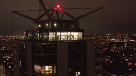 Slide-and-pan-shot-of-top-terrace-of-Castilla-apartment-building-at-night.-Cityscape-in-background.-London,-UK