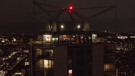 Orbit-shot-around-top-floors-of-Castilla-modern-high-rise-residential-building.-Windows-glowing-into-dark.-London,-UK