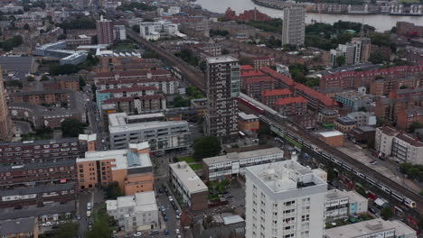 Slide-and-pan-shot-of-town-development.-Aerial-view-of-trains-on-railway-line-in-city.-Skyscrapers-in-modern-business-district-in-background.-London,-UK