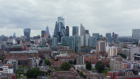 Forwards-fly-over-top-of-tall-building.-Panoramic-view-of-iconic-skyscrapers-in-City-business-hub.-London,-UK
