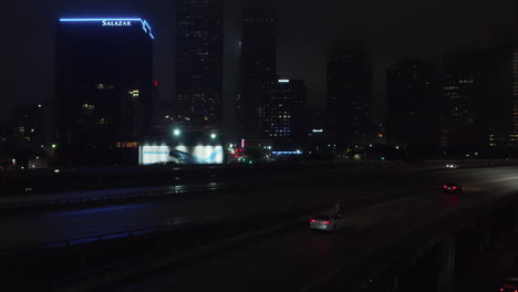 Ascending-drone-view-reveal-low-traffic-on-highway-and-city-lights-in-downtown-at-night.-Dallas,-Texas,-US