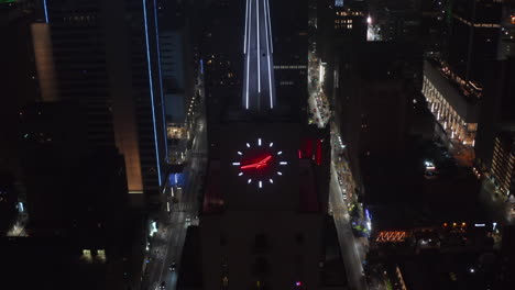 Close-up-view-of-neon-illuminated-spike-and-clock-on-top-of-Mercantile-National-Bank-Building.-Aerial-drone-night-view-tilting-down.-Dallas,-Texas,-US