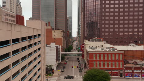 Forwards-reveal-of-street-between-tall-modern-buildings-downtown.-Fly-above-road-with-low-traffic.-Dallas,-Texas,-US