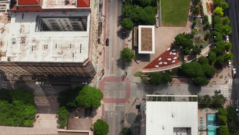 Aerial-birds-eye-overhead-top-down-panning-view-of-downtown-streets-leading-along-public-park.-Dallas,-Texas,-US