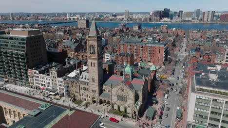 Absteigende-Luftaufnahmen-Der-Alten-Steinkirche-In-Der-Stadtentwicklung.-Breite-Strömung-Des-Charles-River-In-Der-Ferne.-Boston,-USA