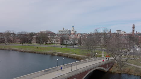 People-walking-on-John-W.-Weeks-Footbridge-over-Charles-river.-Revealing-buildings-in-Harvard-University-campus.-Boston,-USA